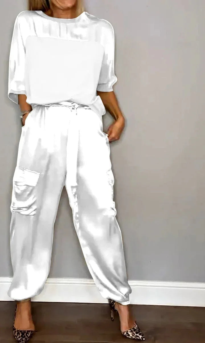 Mujer caminando con conjunto satinado: top suelto que fluye y pantalón cargo, atuendo cómodo y elegante.