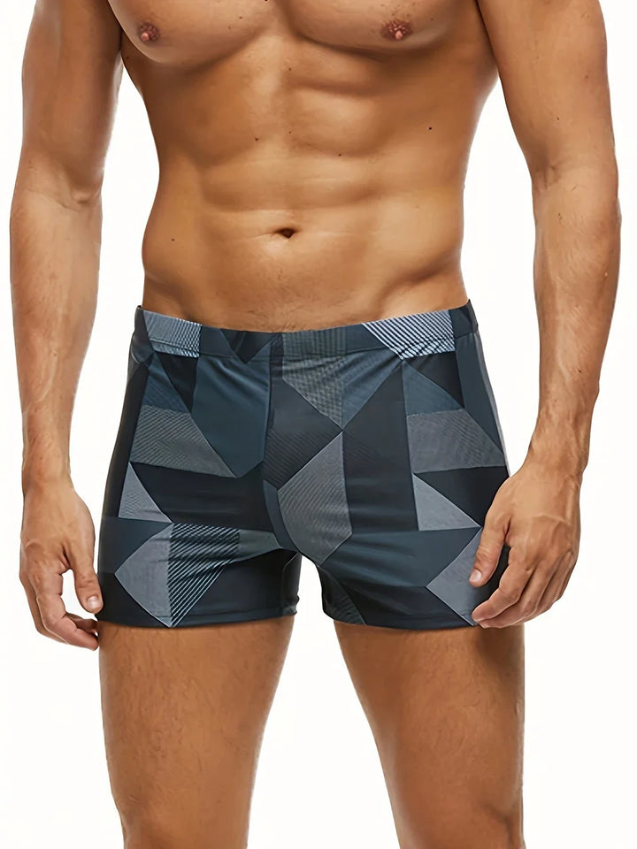 Bañador bóxer hombre moderno con estampado geométrico azul y negro, ideal para playa y piscina.