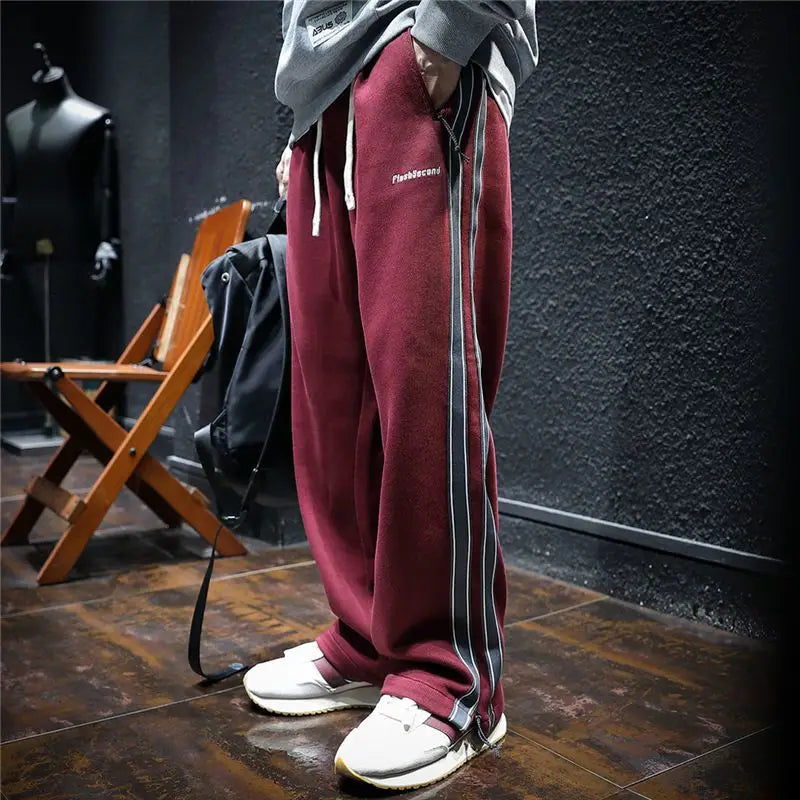 Pantalones anchos negros de hombre con rayas rojas laterales. Ajustables, cremallera, ideal estilo urbano.