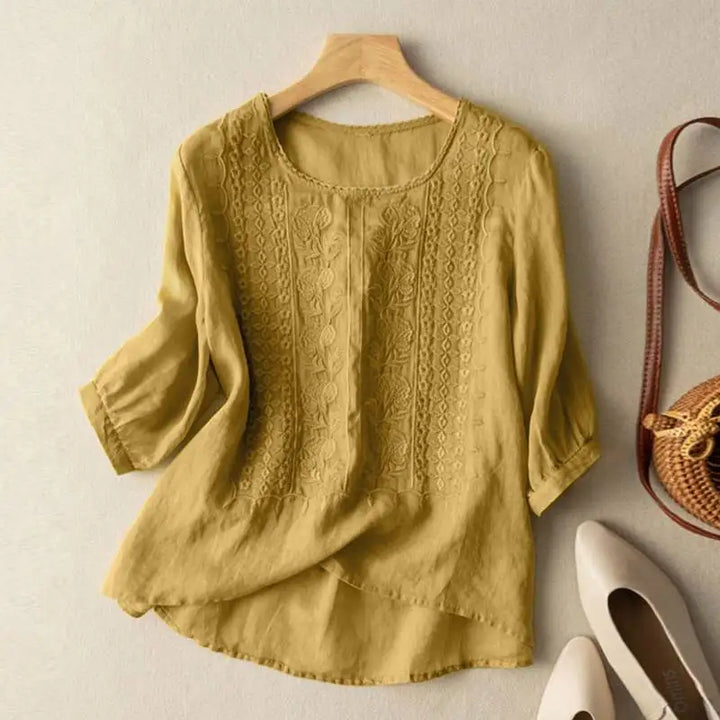 Blusa relajada de mujer blanca con bordados artesanales, manga larga y escote V. Tejido ligero, ideal primavera/verano.