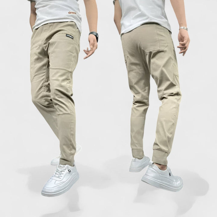 Hombre vistiendo pantalones cargo flexibles con múltiples bolsillos, color caqui, perfectos para comodidad y moda urbana.