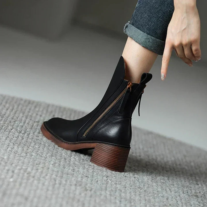 Botines negros para mujer con tacón bloque y cremallera lateral. Piel sintética, diseño elegante.
