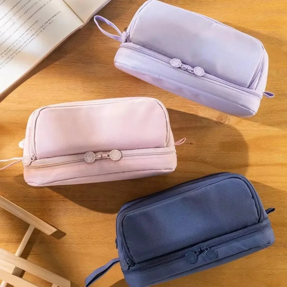 Vista abierta del estuche escolar grande unisex, mostrando sus 4 compartimentos y separador interno.