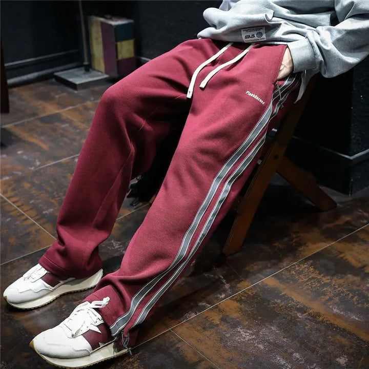 Pantalones anchos de hombre con rayas laterales destacadas, estilo urbano y relajado para el día a día.