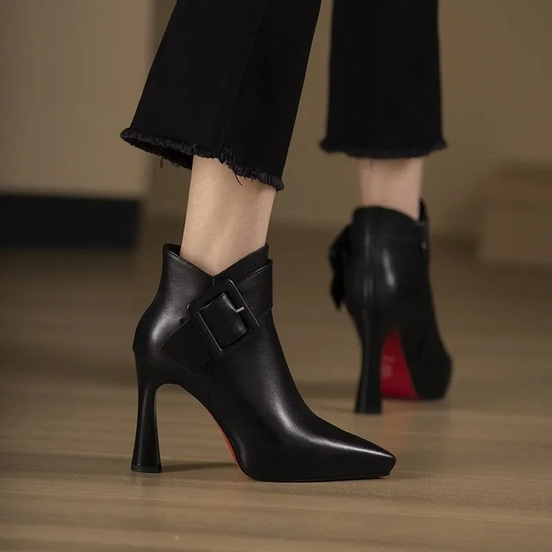 Botín femenino de piel con hebilla decorativa y tacón bloque. Estilo chic para moda de otoño-invierno.