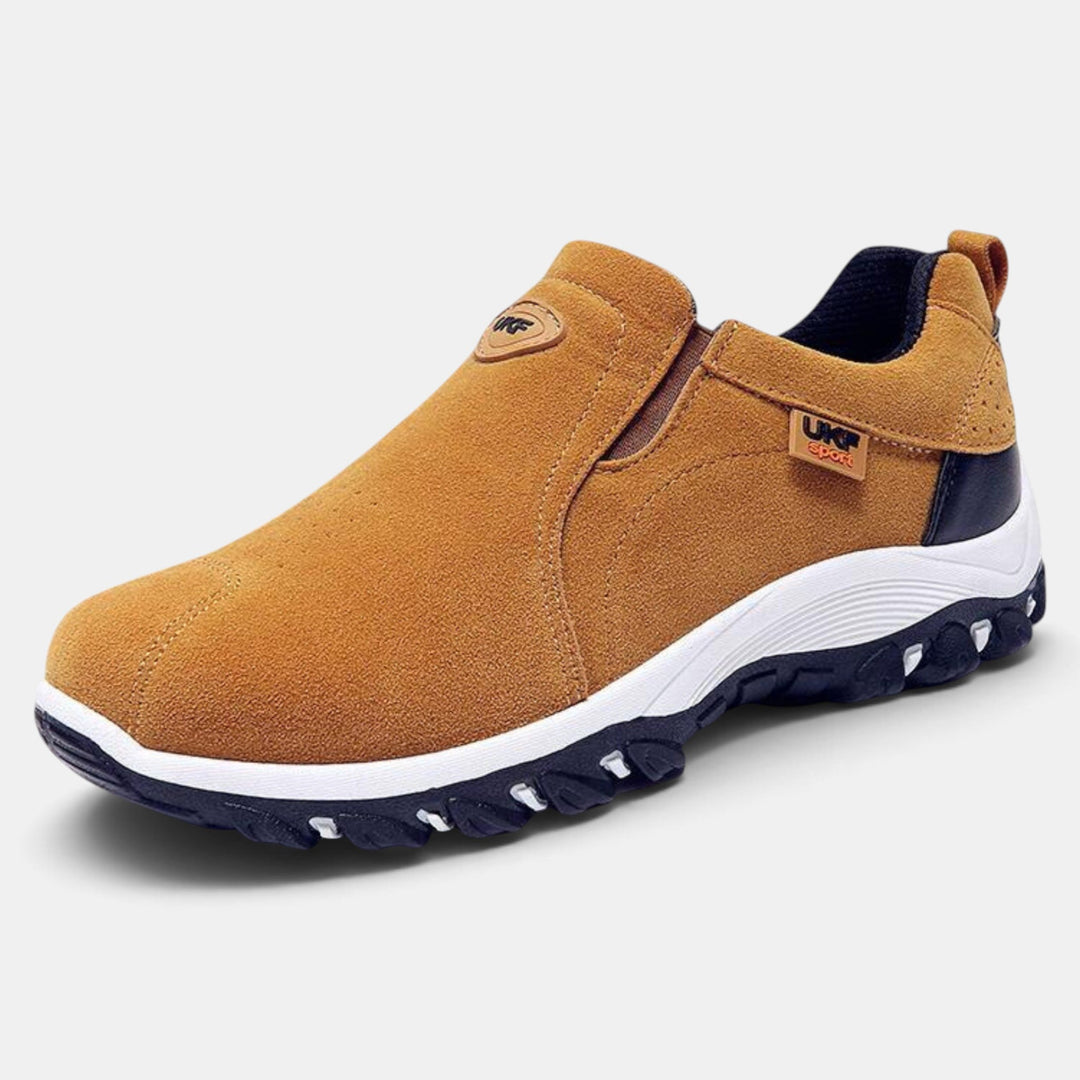 Hombre calzando zapatos slip on negros, perfectos para el trabajo o el ocio, ofreciendo comodidad y paso seguro.