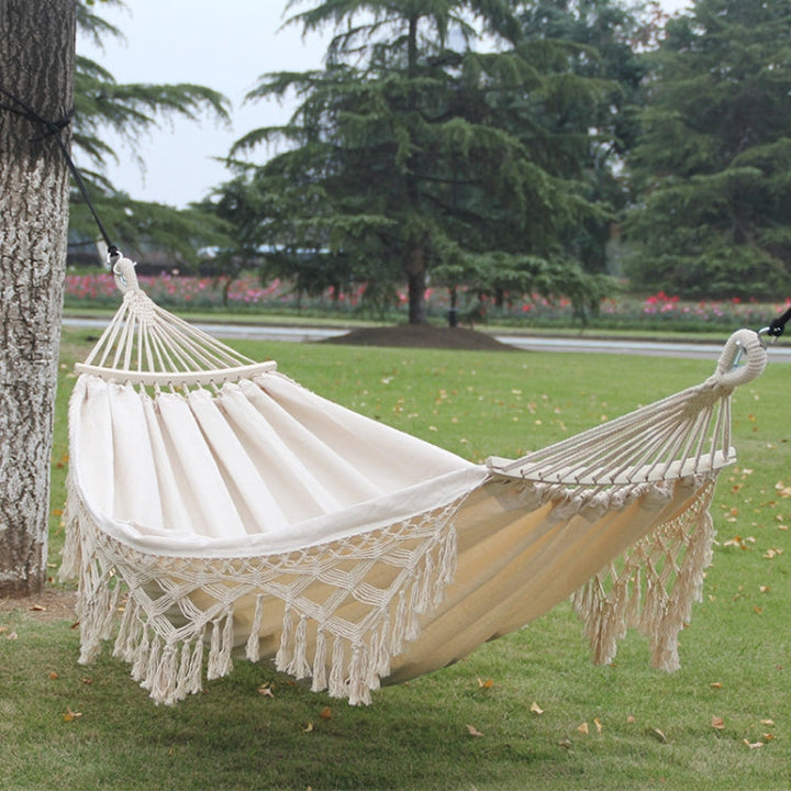 Hamaca doble de lona blanca con flecos, perfecta para el jardín y camping. Ideal para relajación exterior.