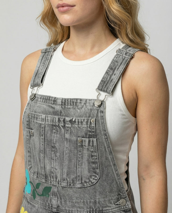 Detalle de peto de mezclilla para mujer con patrón floral vibrante y tirantes ajustables, look fresco.