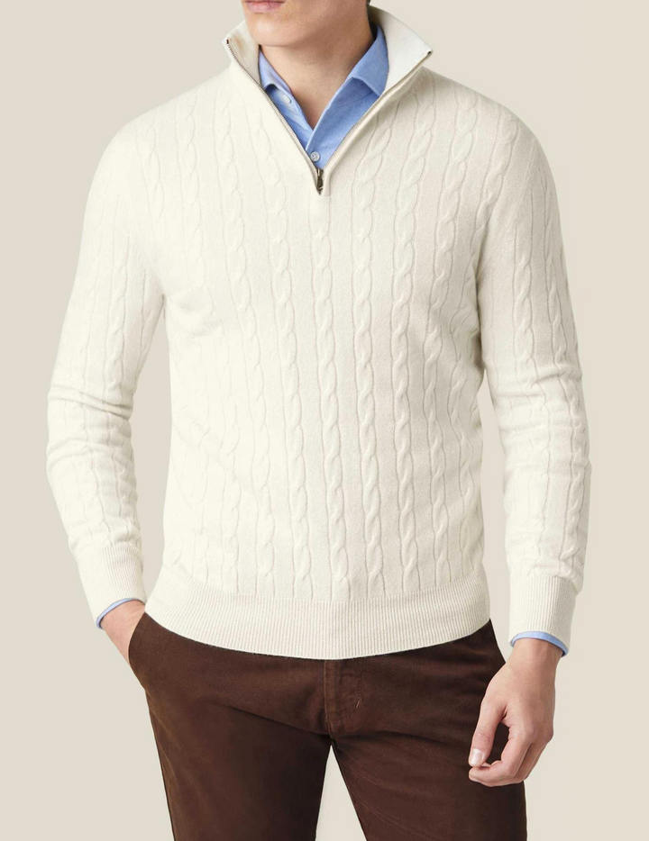 Hombre con suéter trenzado negro, cuello alto y cremallera, moda versátil invernal.