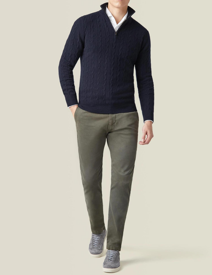 Hombre vistiendo suéter trenzado de cuello alto y cremallera, look casual y elegante.