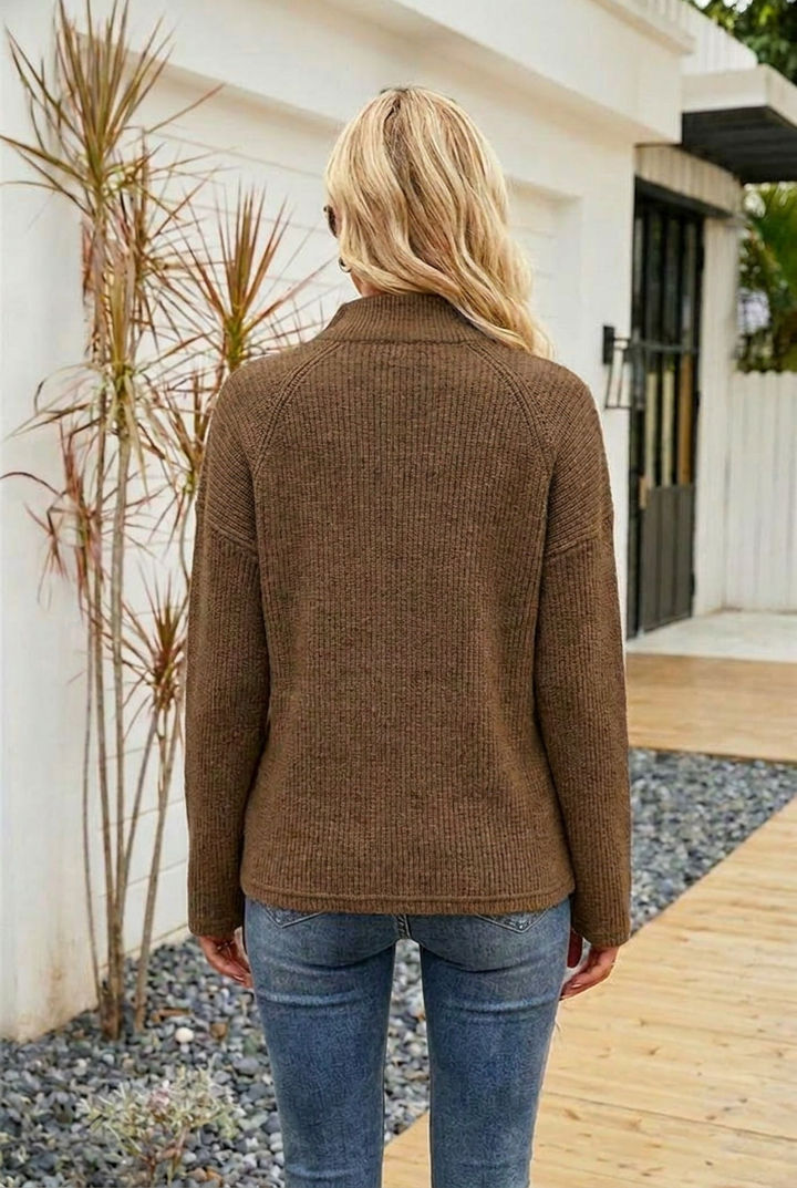 Mujer luciendo jersey de punto gris, cuello camisa con cremallera, manga larga, para un estilo casual de invierno.