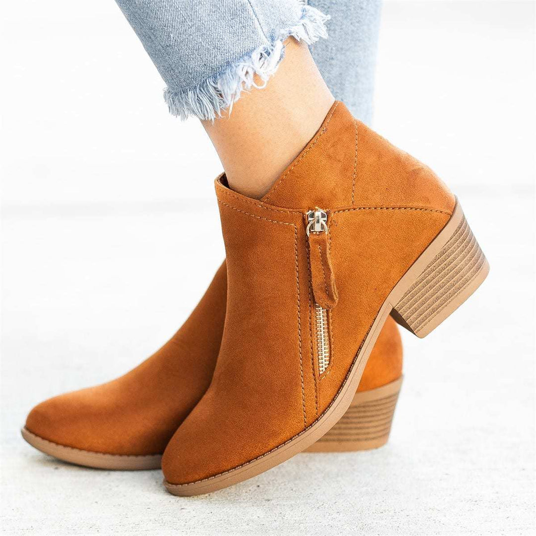 Primer plano de botines de mujer de ante suave con tacón de madera robusto, calzado de moda para invierno.