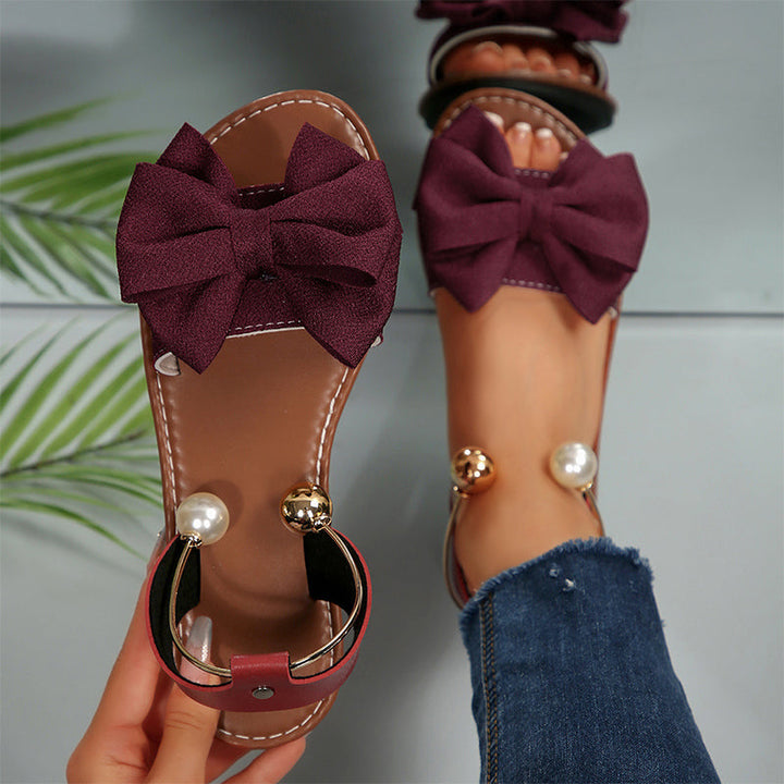 Calzado de moda para mujer: sandalias planas con adorno de lazo y perlas.