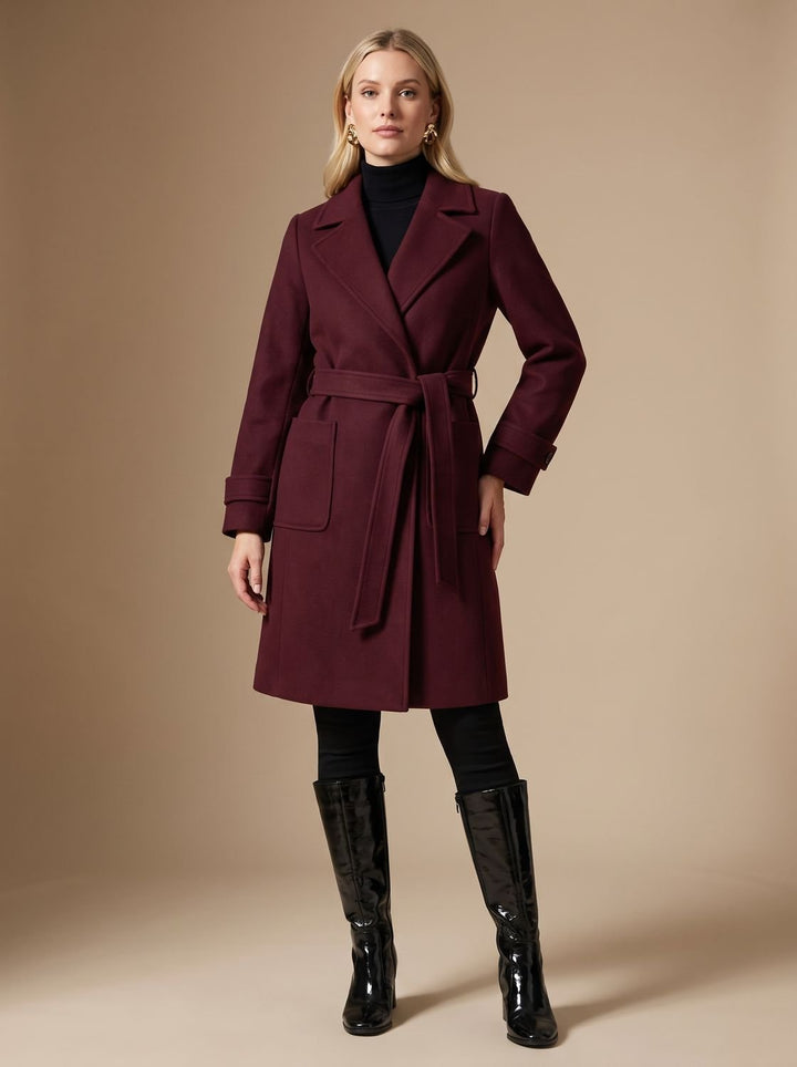 Mujer luciendo abrigo largo burdeos cruzado con cinturón. Ropa de abrigo elegante para invierno.