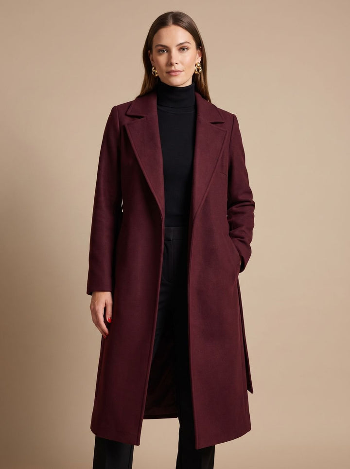 Abrigo de mujer burdeos, largo y cruzado, con cinturón. Aporta elegancia y calidez en otoño e invierno.
