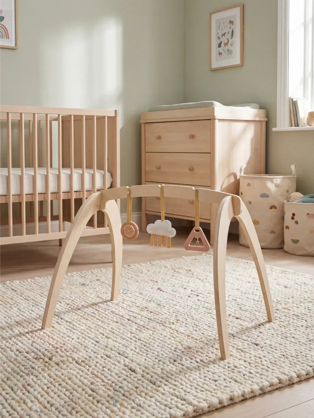 Bebé interactuando con arco de juego de madera y juguetes colgantes, estimulación temprana.