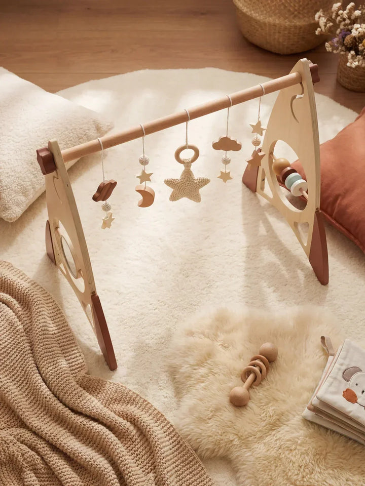 Arco de juegos de madera con cohete y estrellas, ideal para la estimulación temprana del desarrollo del bebé.