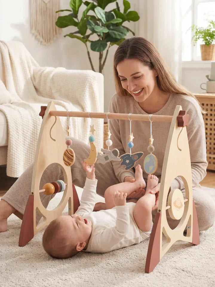 Arco de juegos de madera: cohete y estrellas. Gimnasio sensorial para estimulación visual y táctil del bebé.