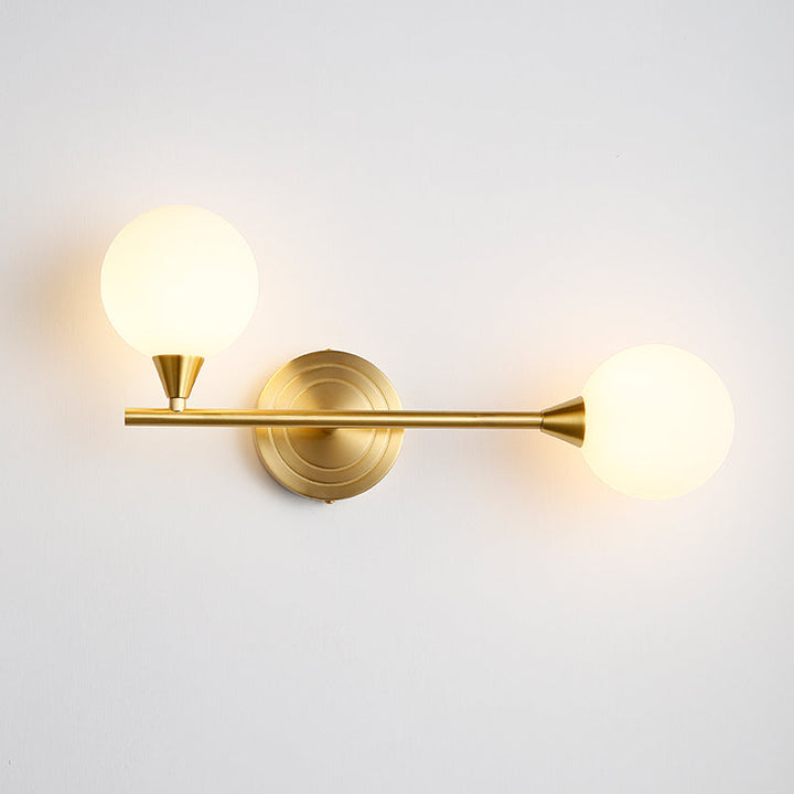Aplique de pared con diseño moderno. Latón y dos globos de cristal blanco. Elegancia sencilla.