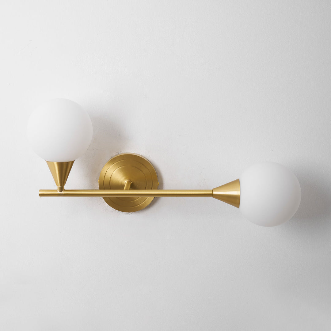 Lámpara de pared en latón, con dos difusores de cristal blanco en forma de globo. Iluminación moderna.