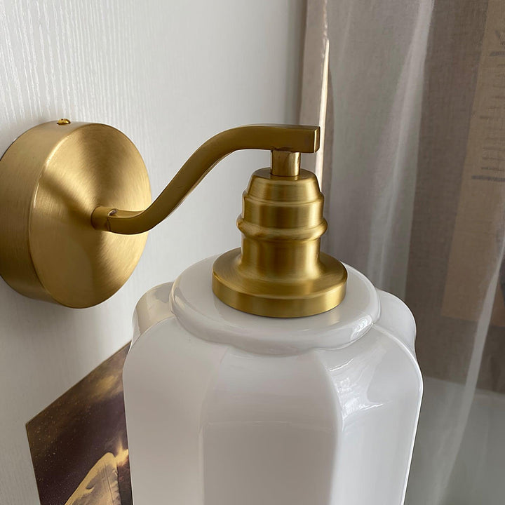 Lámpara compacta de latón y cristal, apta para instalación en pared.