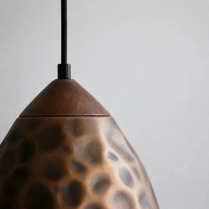 Primer plano de la textura martillada en lámpara colgante de cobre, estilo industrial decorativo.