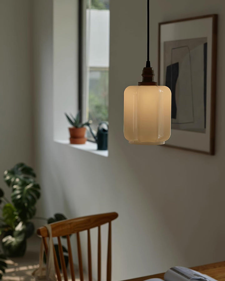 Lámpara colgante con luz ambiente cálida, pantalla de cristal blanco que difunde la luz uniformemente.