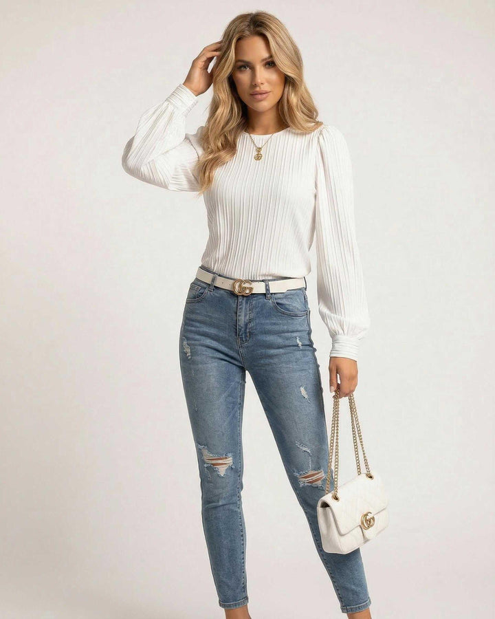 Modelo luciendo blusa blanca plisada de manga larga, un top versátil que combina elegancia y comodidad para mujer.