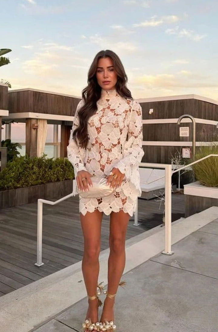 Vestido corto de encaje floral blanco para mujer con cuello alto y manga larga, ideal para cóctel y fiesta.