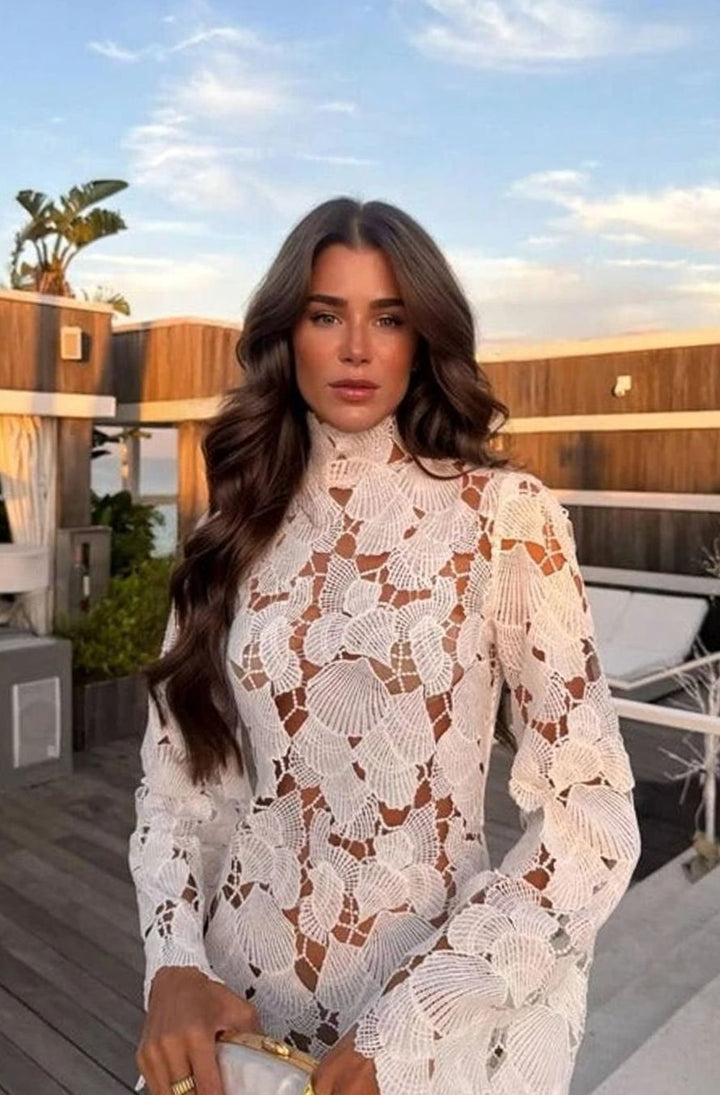 Vestido entallado corto de encaje floral blanco, con cuello alto y manga larga, ideal para ocasiones especiales.