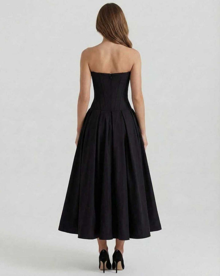 Modelo mujer con vestido midi Cleo negro, silueta A sin tirantes, perfecto para celebraciones o eventos de noche.