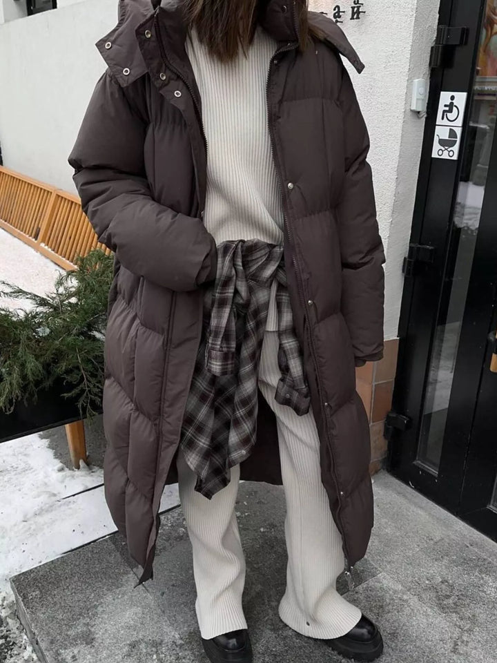 Abrigo largo acolchado para mujer, vista trasera, con cinturón que estiliza, ideal para el invierno.