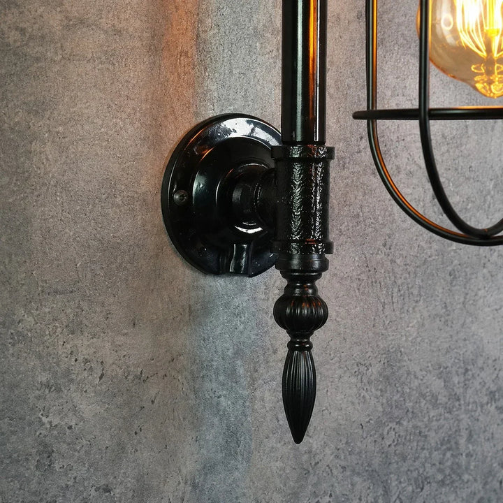 Aplique de pared metálico negro, estilo industrial y vintage, con jaula para luz decorativa.