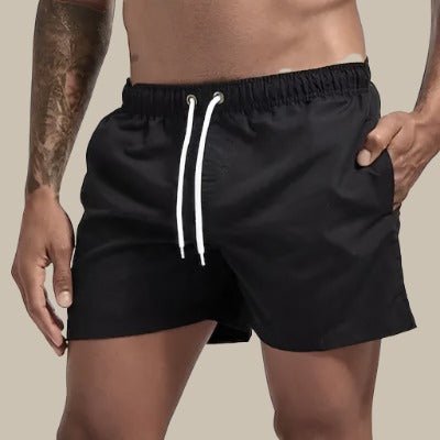Hombre disfrutando en la playa con bañador corto de natación casual y moderno, ideal para el verano.