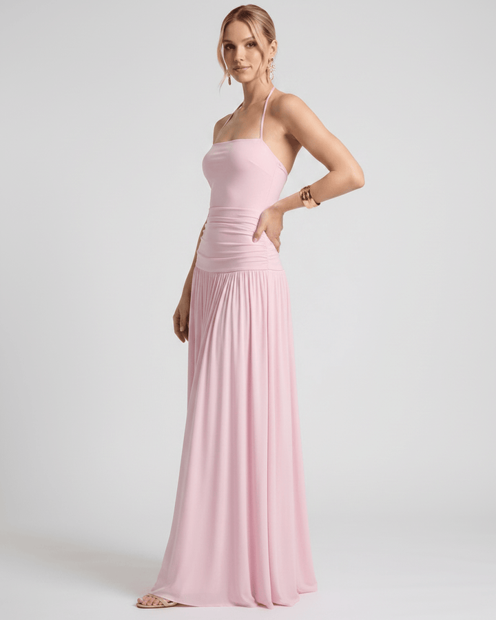 Mujer en un jardín con vestido maxi de verano. Cuello halter, fluido y moda femenina.