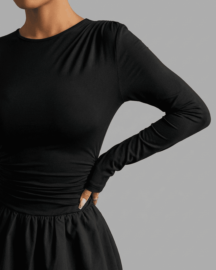Vestido negro ajustado de manga larga con detalles de volantes en el bajo. Mini vestido chic y favorecedor para mujer.