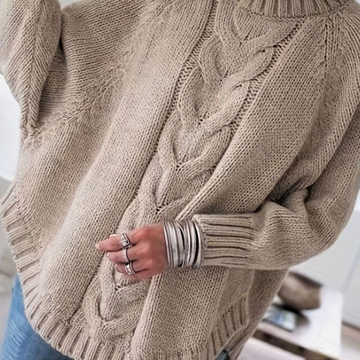 Elegante jersey oversize de punto trenzado para mujer, cuello alto, cálido y moderno.