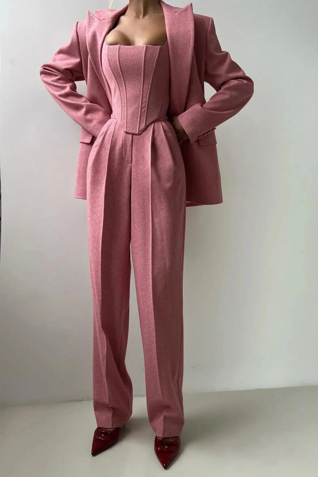 Vista frontal de conjunto elegante mujer rosa. Tres piezas entalladas con top ajustado, moda actual.