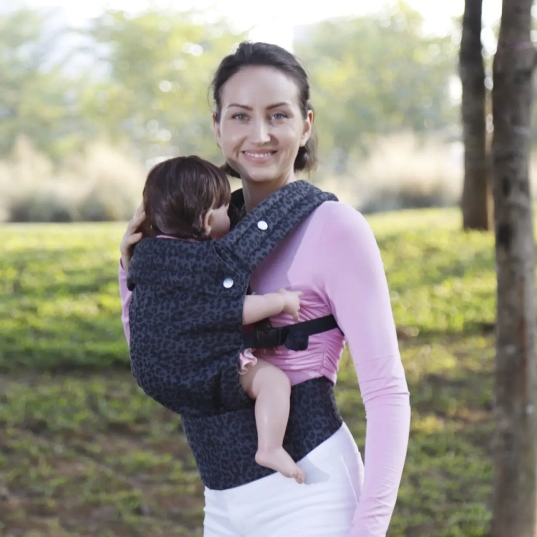 Pareja activa paseando con su bebé en un portabebés ergonómico y ajustable, disfrutando al aire libre.
