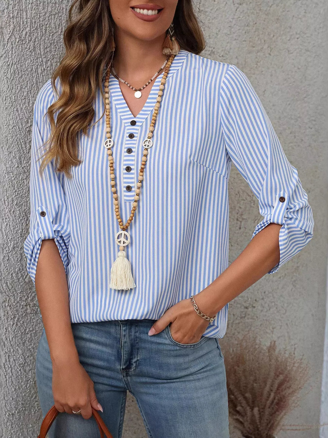 Modelo de mujer vistiendo blusa de rayas, cuello V, manga enrollable, look veraniego.