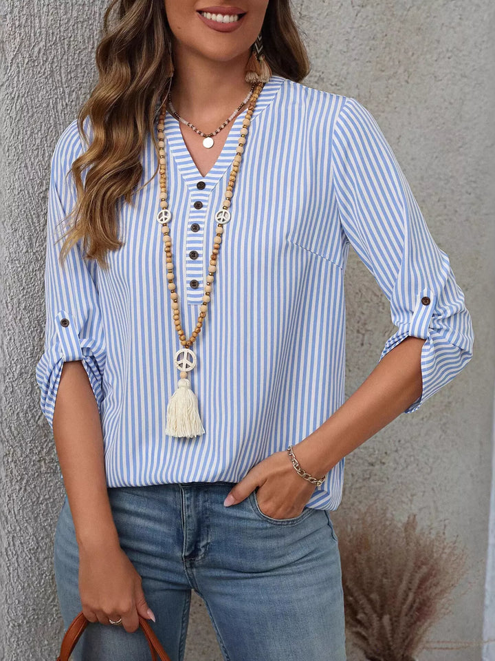 Modelo de mujer vistiendo blusa de rayas, cuello V, manga enrollable, look veraniego.
