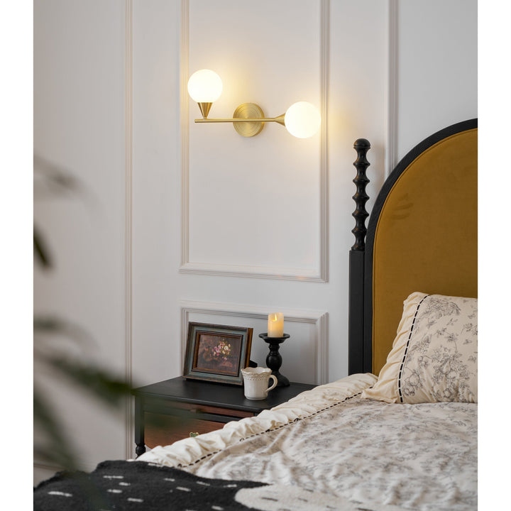 Aplique de pared de latón para iluminación interior. Dos globos de cristal blanco y estilo actual.