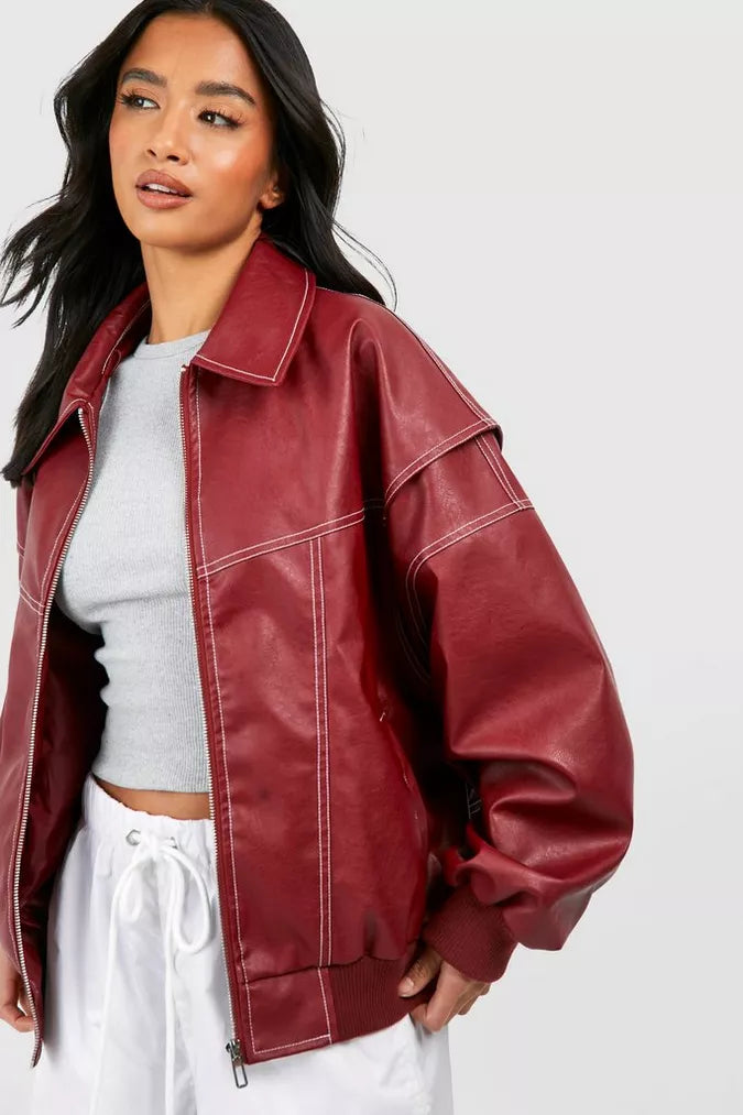 Chaqueta bomber oversize de mujer en cuero sintético negro con llamativas costuras contraste blancas.