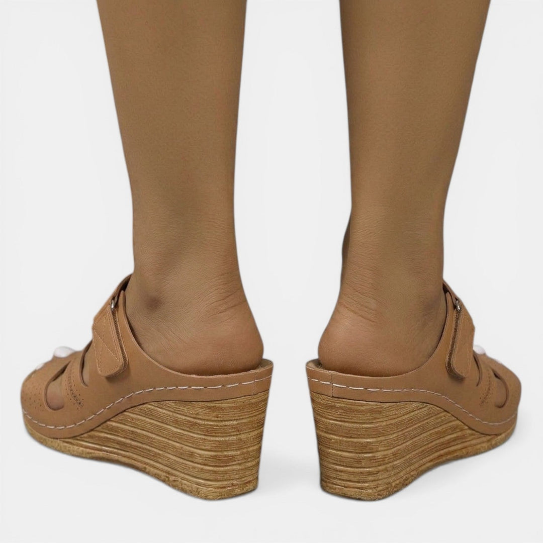 Mujer usando sandalias ortopédicas de cuña. Perfectas para paseos de verano, combinan estilo y comodidad.