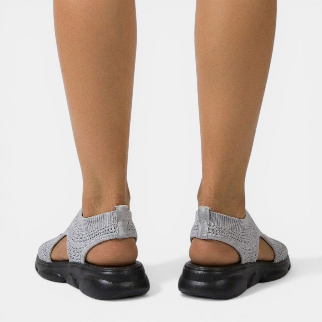 Mujer usando sandalias ortopédicas. Calzado cómodo, transpirable y plano para paseos veraniegos con soporte.