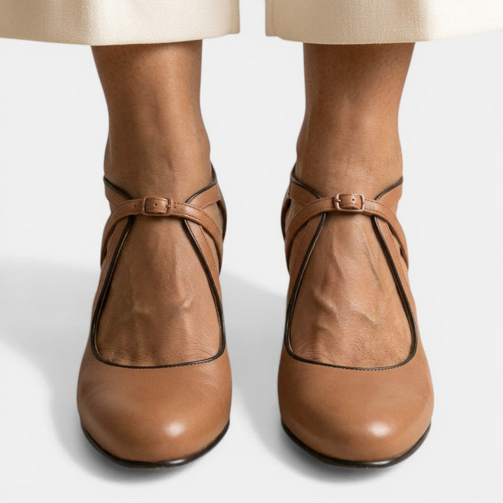 Detalle de sandalias T-strap para mujer, diseño clásico y cierre de hebilla, ideal para fiestas.