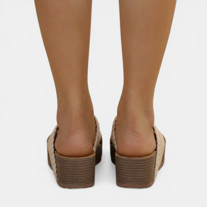 Mujer luciendo sandalias cruzadas trenzadas. Calzado femenino cómodo para moda verano y estilo casual.
