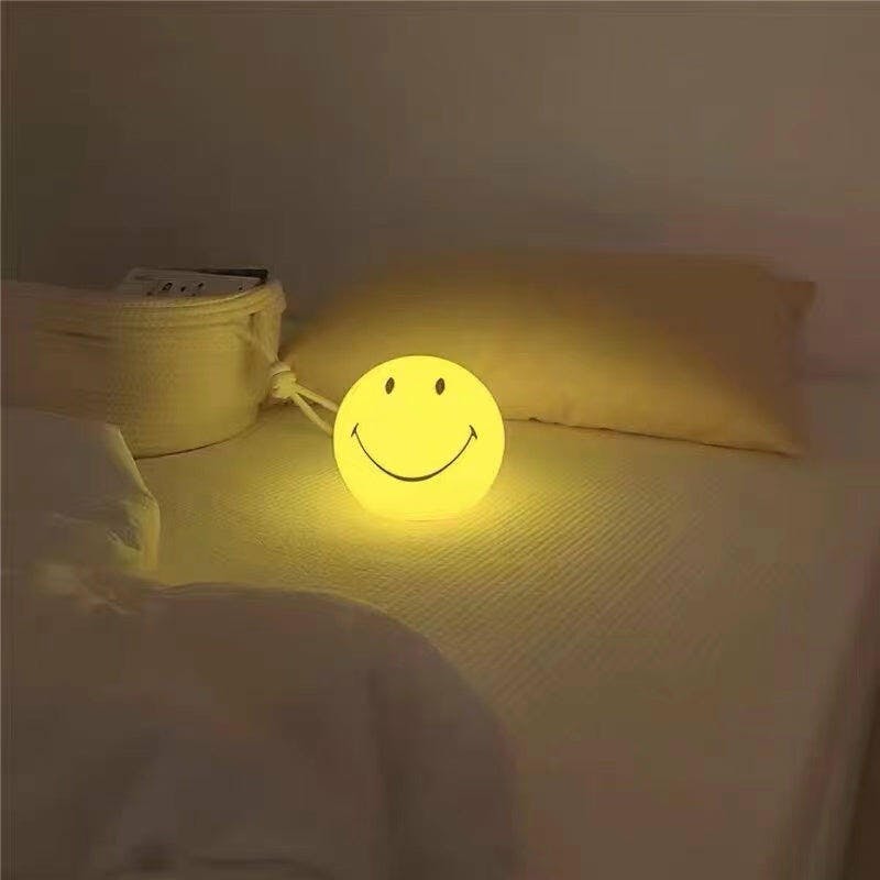 Moderna lámpara de mesa LED amarilla con cara sonriente. Añade un toque de luz y alegría a cualquier hogar.