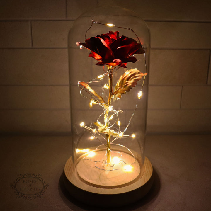 Regalo de aniversario: rosa dorada eterna con luz LED bajo cúpula de vidrio, símbolo de amor duradero.