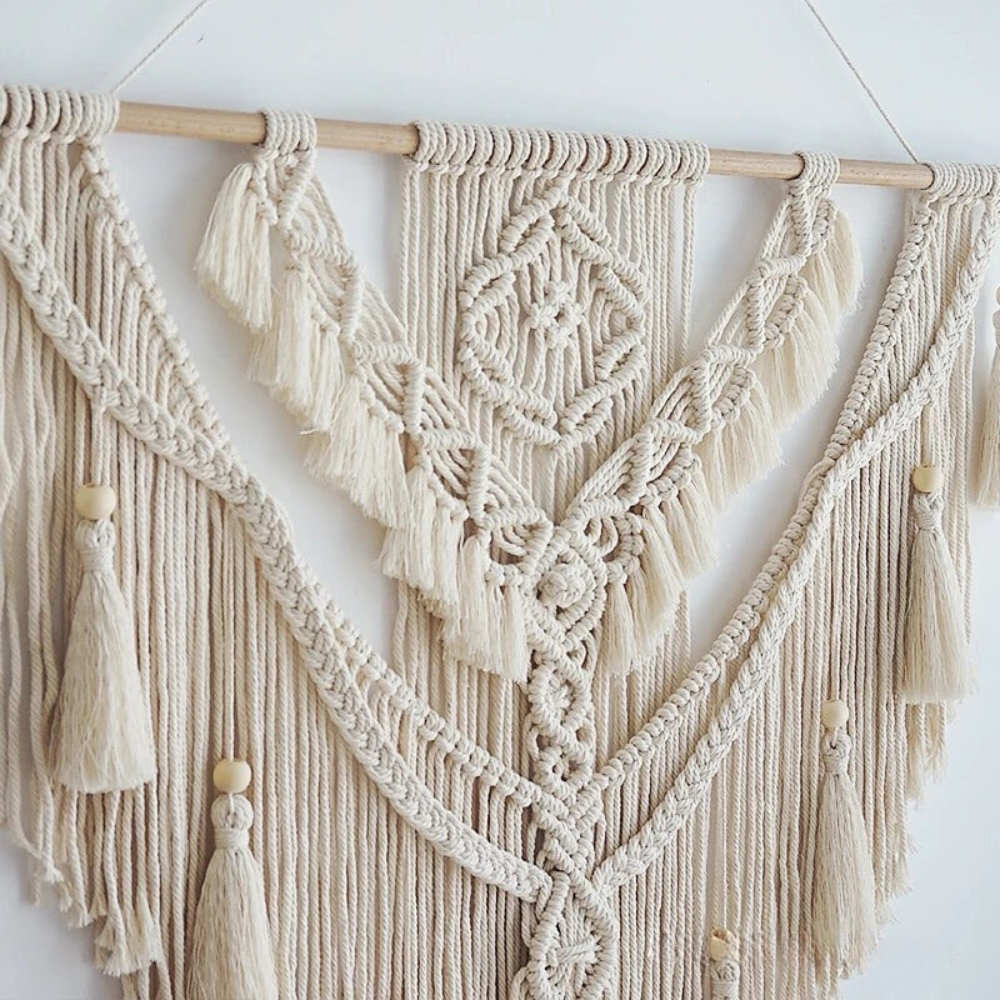 Decoración de pared de macramé estilo boho escandinavo, colgante hecho a mano con detalles tejidos en beige y amarillo.